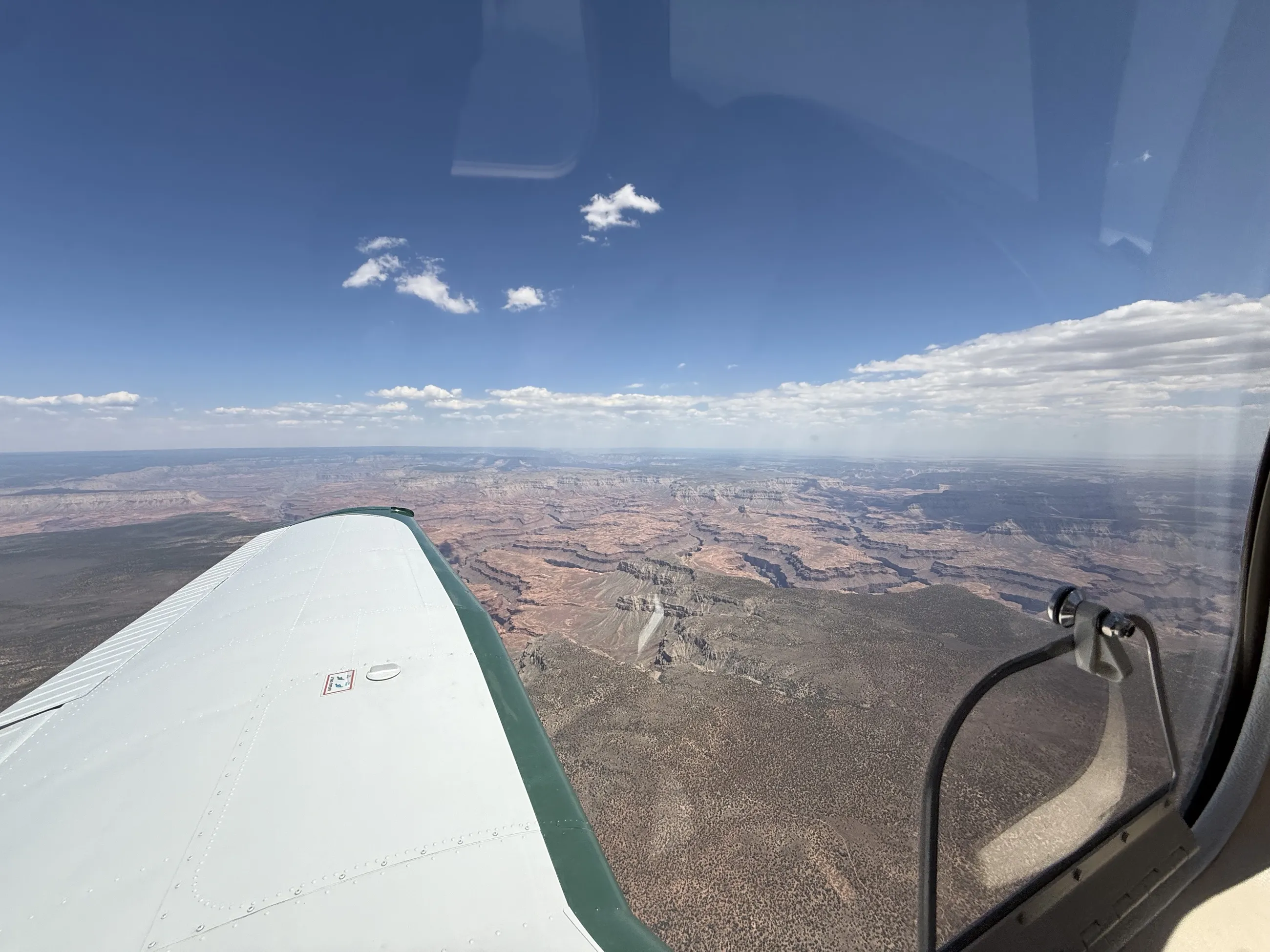 The Grand Canyon under a band of cloud, seen past the wing