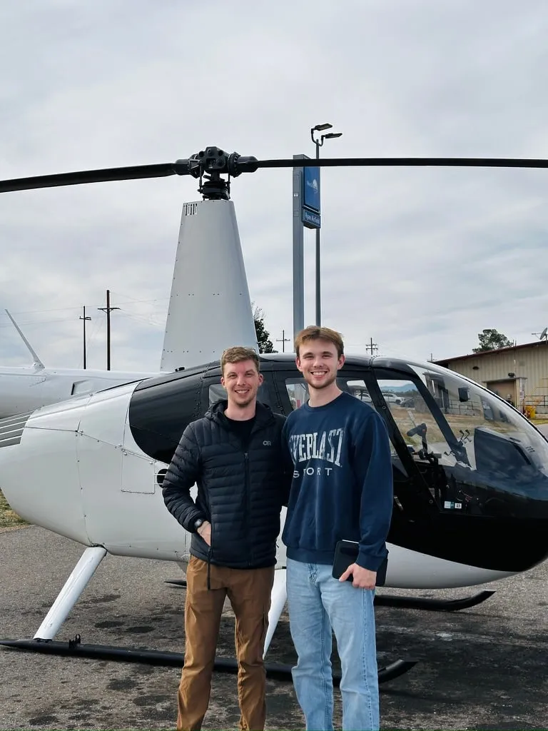 Brandon and a friend beside a Robinson R44 helicopter on the ramp