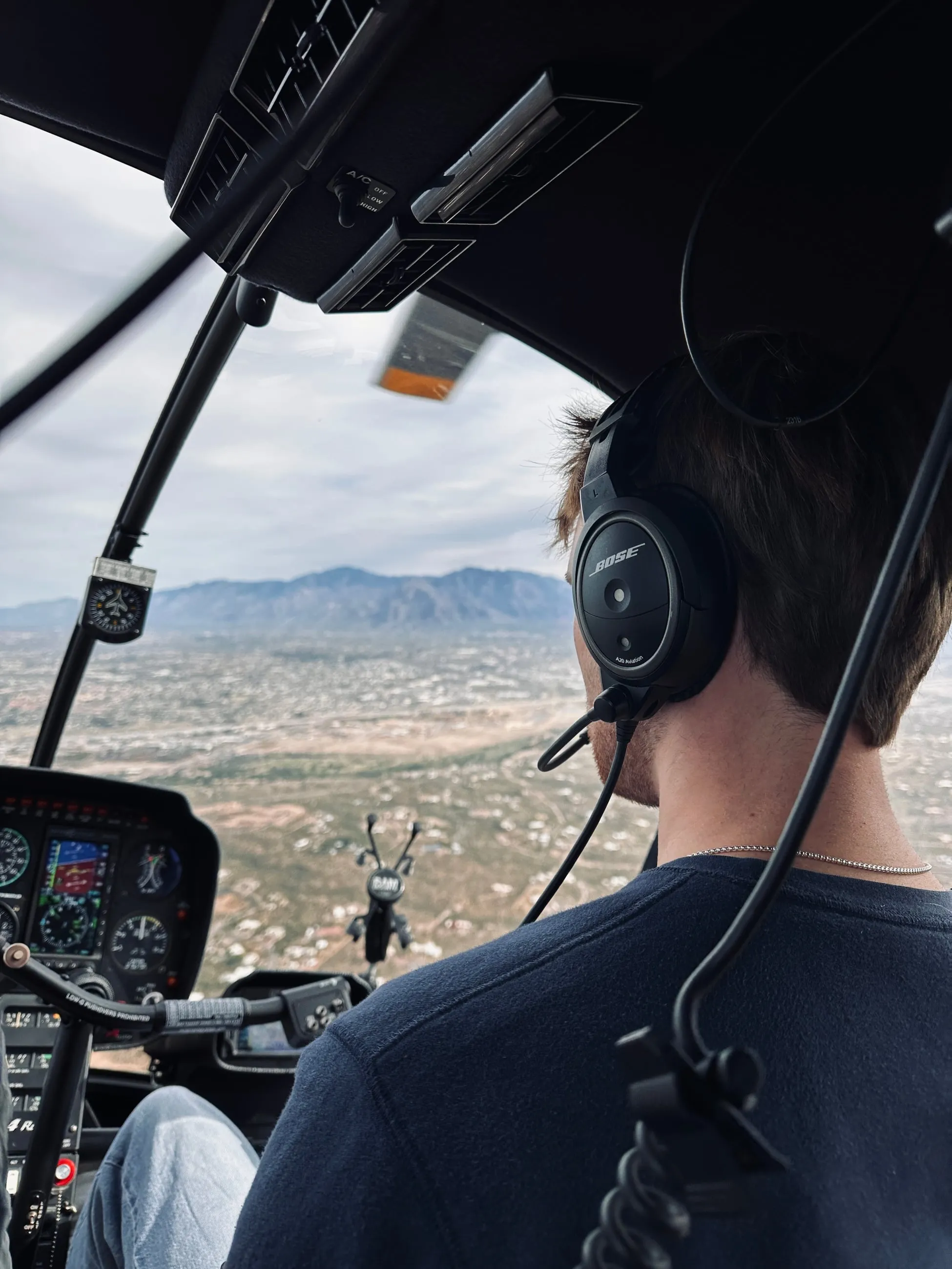 In the right seat of a Robinson R44 over the desert valley