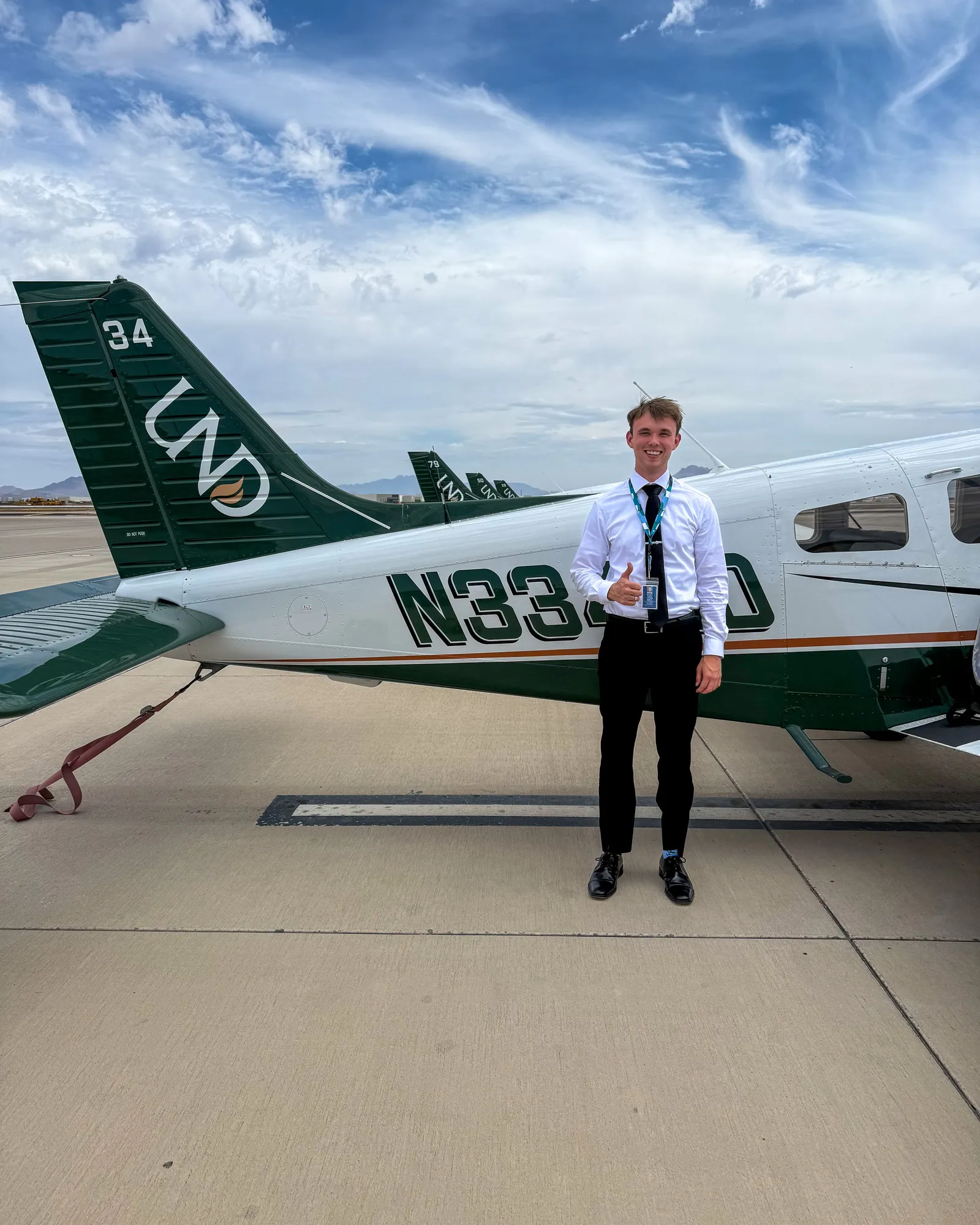 Brandon in shirt and tie beside a UND Piper Archer at Phoenix