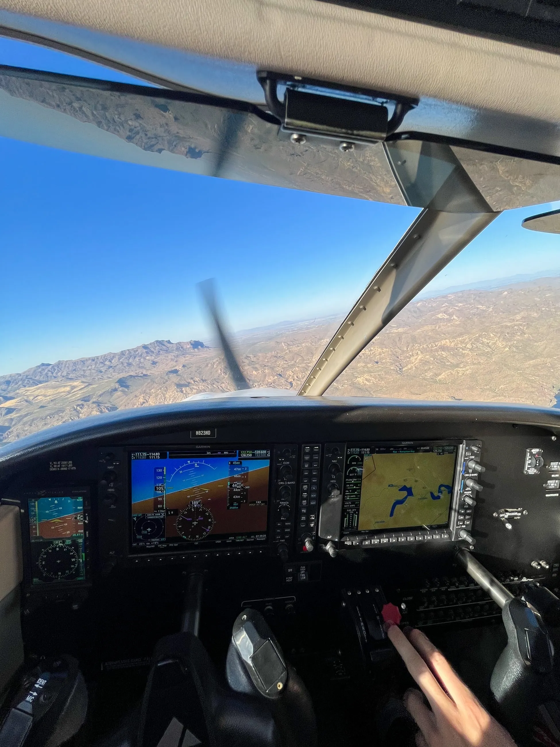 The panel in cruise over Arizona mountain country, prop blurred against the sky