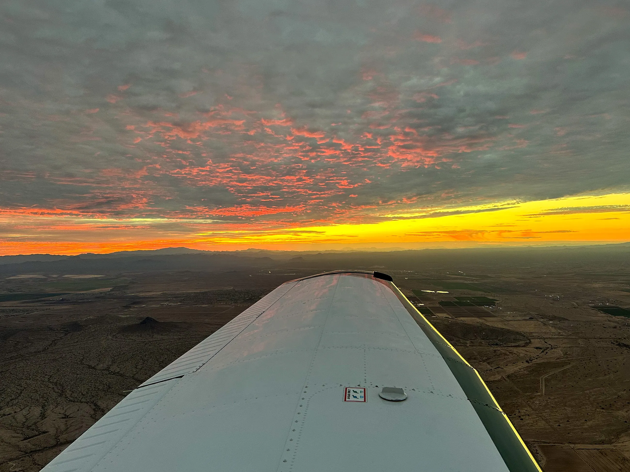 The last band of sunset on the horizon over the desert, the wing in the foreground